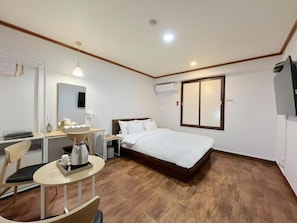 A bedroom with a bed, bedside table, chair, and a small table with a coffee maker. - METRO MOTEL (Pocheon)