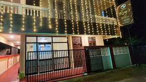 A hotel with a reception area, a balcony with string lights, and a sign indicating it offers rooms and a restaurant. - Hotel Roy's (Port Blair)