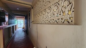 A corridor with a decorative wall, a tiled floor, and a door leading to another room. - Hotel Roy's (Port Blair)