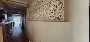 Um corredor com parede decorativa, piso em azulejo e porta que dá para outro quarto.