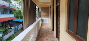 Varanda com piso estampado, guarda-corpo e vista para uma rua com edifícios e áreas verdes.