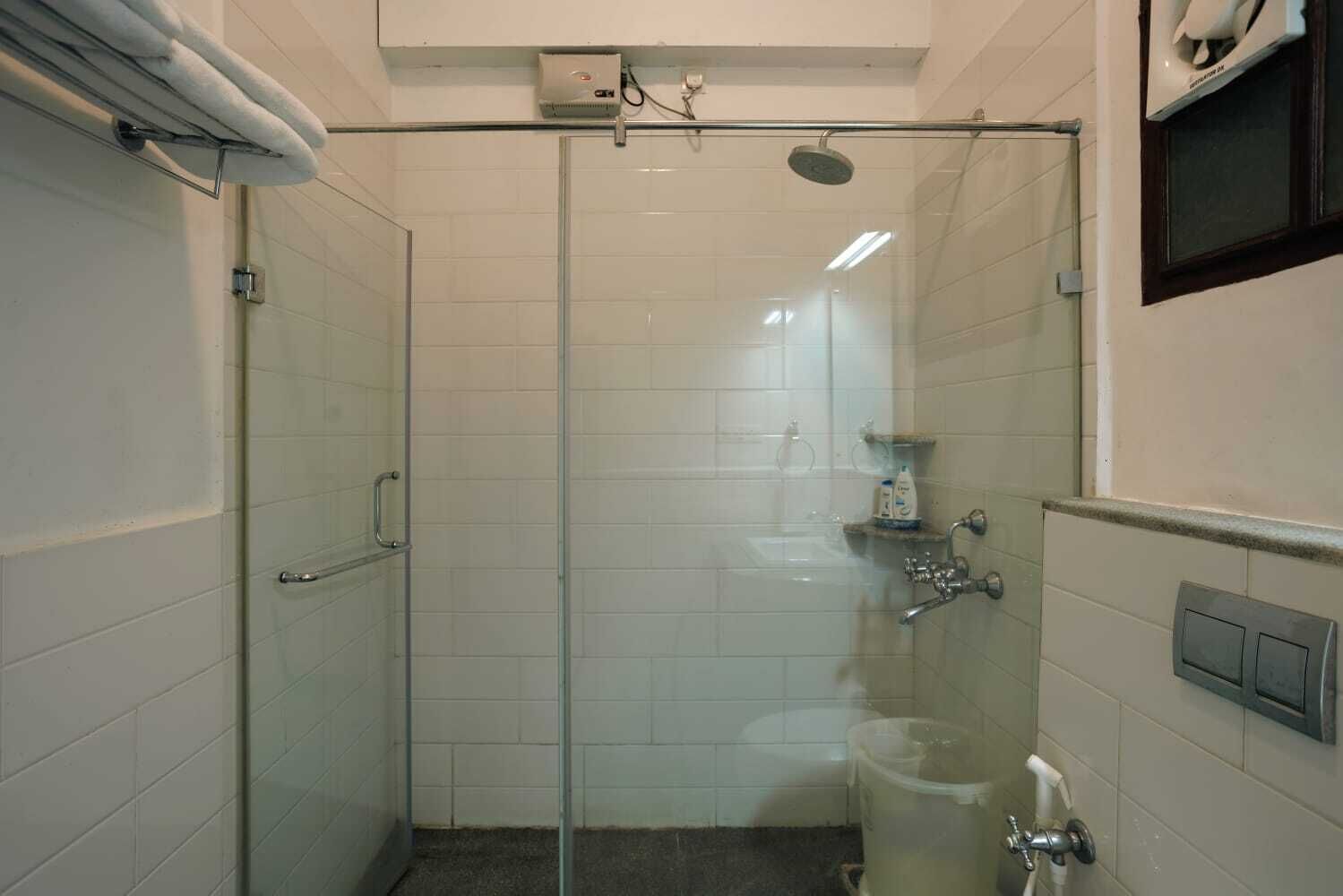 Ducha envuelta en vidrio, con un cabezal de ducha manual y un grifo empotrado.