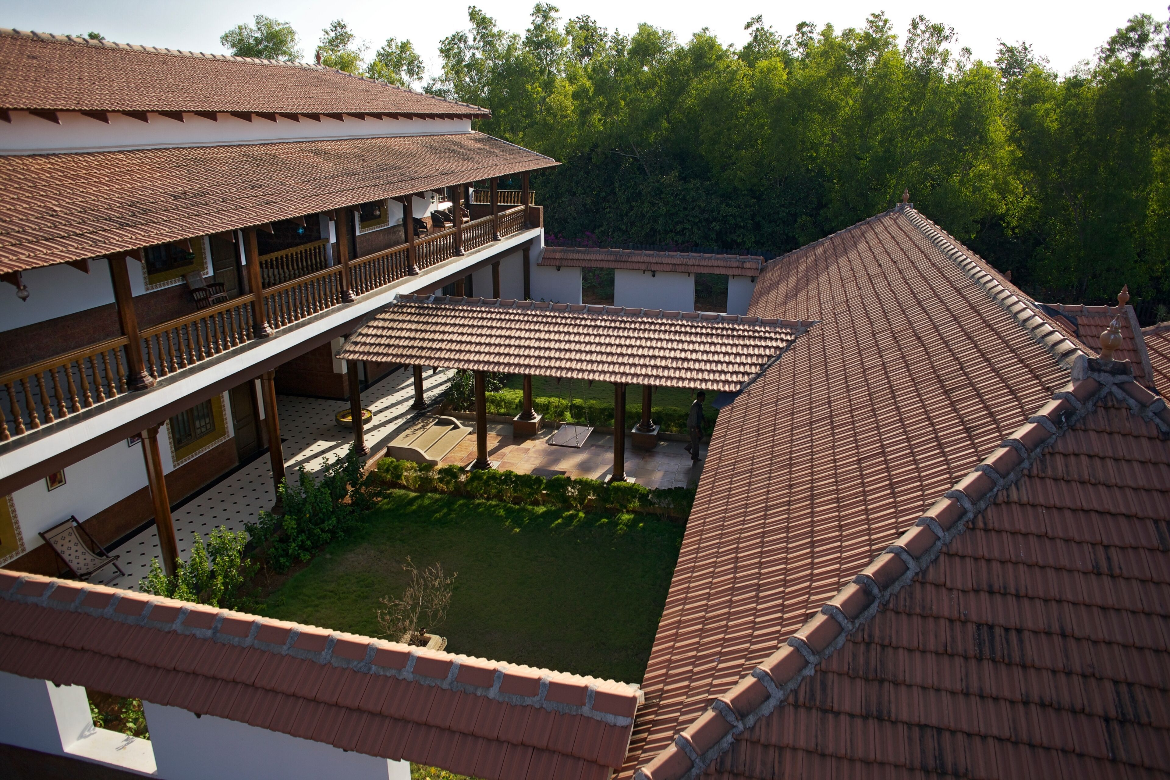 A traditional building with a tiled roof, a covered patio area, and a courtyard surrounded by greenery.