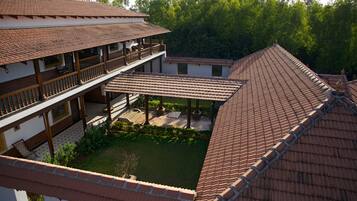 A traditional building with a tiled roof, a covered patio area, and a courtyard surrounded by greenery.