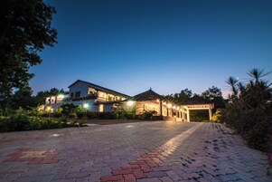 A paved pathway leading to a building with multiple illuminated windows and a covered entrance.