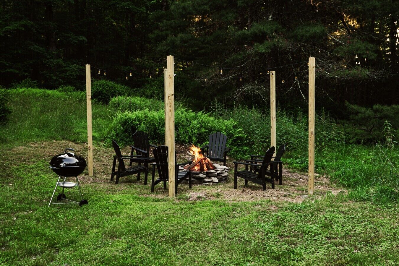 Un espacio al aire libre con sillas y una parrilla, rodeado de vegetación.