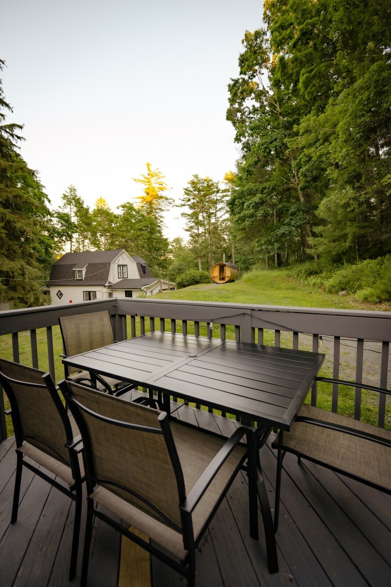 Une terrasse extérieure avec une table et des chaises, entourée d’une rambarde en bois.