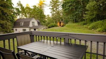 Une terrasse extérieure avec une table et des chaises, entourée d’une rambarde en bois.
