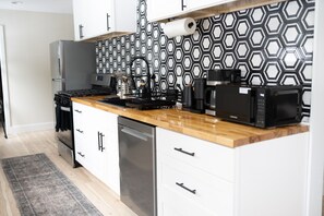 Una cocina moderna con un salpicadero de diseño hexagonal, electrodomésticos de acero inoxidable y encimera de madera.