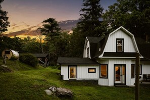 Une maison à deux étages avec un porche à l’avant, un garage et un petit abri de jardin.