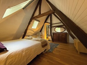 A cozy attic bedroom with a sloped ceiling, a bed, a chair, and a small desk. - Lazy Lane (Gruchet-Saint-Siméon)