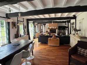 Une pièce spacieuse avec un plancher en bois, une table à manger avec des chaises, un canapé et une cheminée.