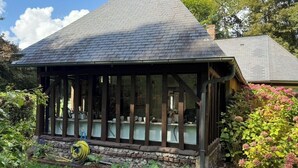 Ein überdachter Außenbereich mit Steinunterbau, Holzbalken und Dach.