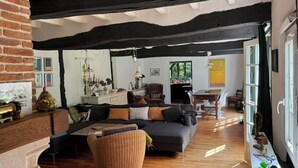 Ein Zimmer mit Holzboden, einer Couch, einem Korbsessel, einem Tisch und einem Fenster.