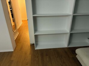 Ein Zimmer mit Holzboden, einer weißen Tür und einer weißen Regaleinheit mit mehreren Fächern.