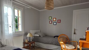 Un dormitorio con dos camas, una silla, una lámpara y una pared con marcos de cuadros.