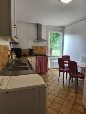 Eine Küche mit Spüle, Herd und einem Essbereich mit Stühlen und Tisch.