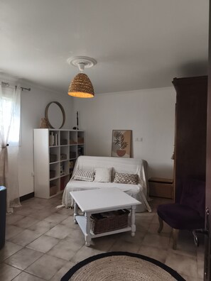 Ein Schlafzimmer mit einem Bett, einer wei ßen Kommode, einem Bücherregal, einer Hängelampe und einem Sessel.