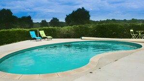 Una piscina con dos sillas de descanso y una mesa.
