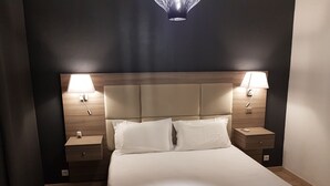 Een hotelkamer met een groot bed, twee nachtkastjes en twee wandlampen.