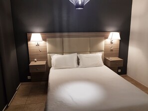 Ein Hotelzimmer mit einem großen Bett, zwei Nachttischen und zwei Wandlampen.