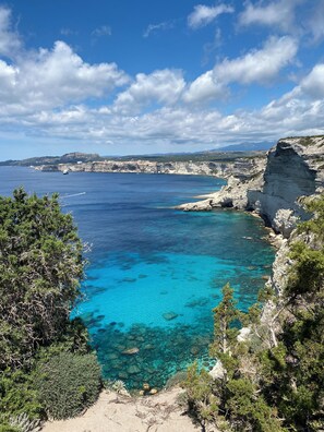 A coastal landscape with clear blue waters, rocky cliffs, and sparse vegetation. - 150 m² air-conditioned detached villa near Porto Vecchio (San-Gavino-di-Carbini)