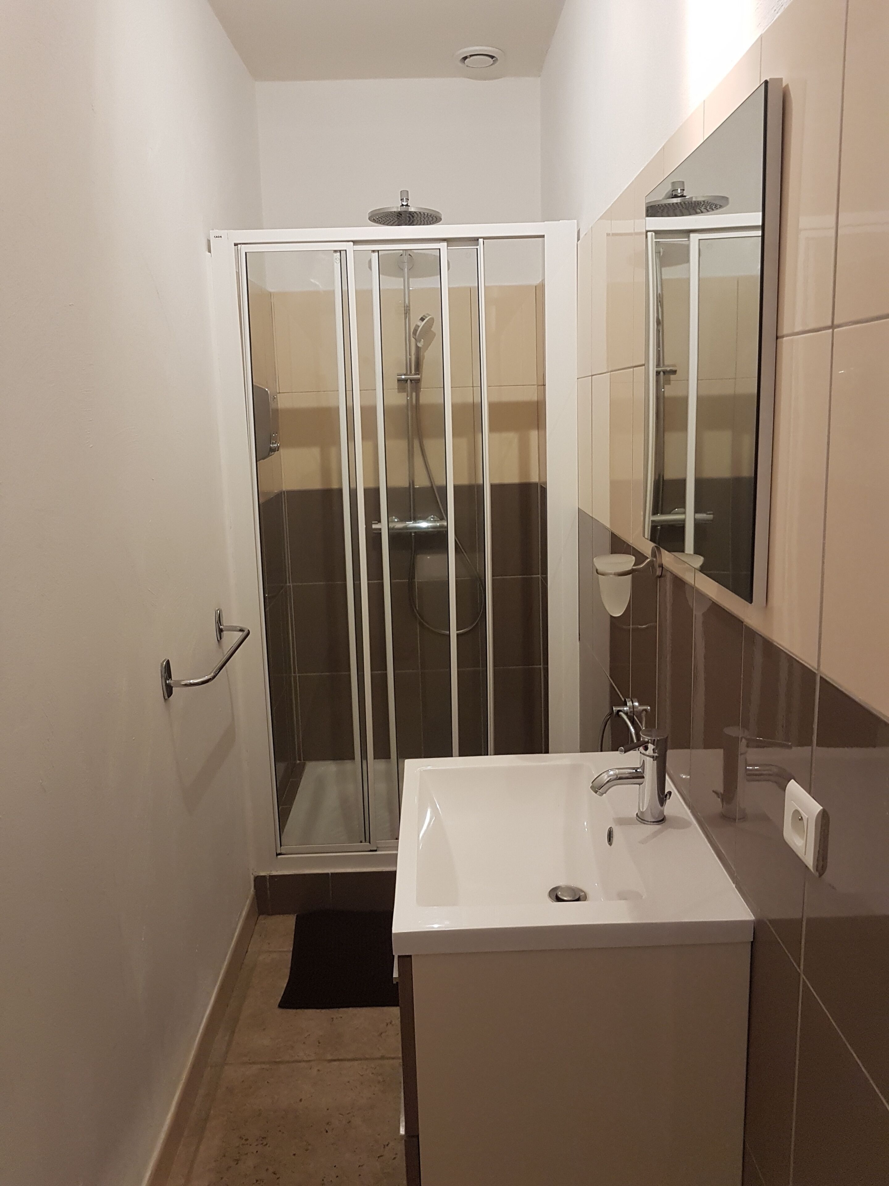 A bathroom with a glass-enclosed shower, a white sink, and a mirror.