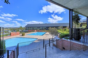Un espace piscine sur le toit, comprenant deux piscines, un espace salon couvert et une vue sur le paysage environnant.