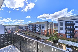 Un immeuble résidentiel à plusieurs étages, doté d’un espace de stationnement, de balcons et offrant une vue dégagée sur le ciel.