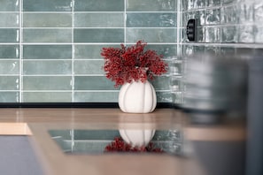 Eine weiße Vase mit roten Blumen auf einer spiegelnden Fläche.