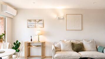 Un salon moderne avec un canapé, une table à manger et une lampe.