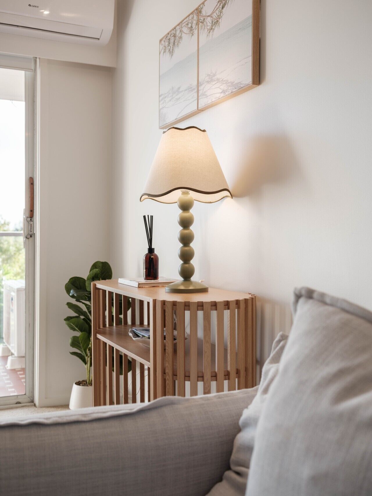 Ein Zimmer mit einem Holzkonsolentisch, einer Lampe, einem Topfpflanzen und einem gerahmten Bild an der Wand.