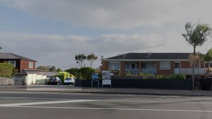 A residential street with houses, parked cars, and a 'SOLD' sign. - Walk to Beach | Sky Tower & Ocean Sunset Views | ✨Sage & Sea by Homello✨ (Devonport)