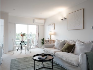 Un salon comprenant un canapé, une table basse et un coin repas avec des chaises.