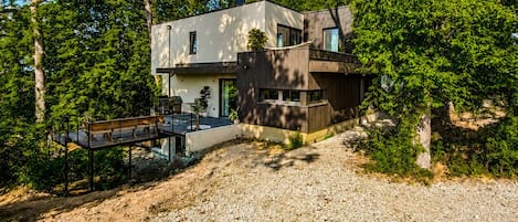 A modern house with a gravel driveway, surrounded by trees.