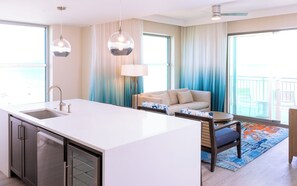 A modern hotel room with a kitchen island, a sofa, and a dining table. - 2-Bedroom Signature Condo in Myrtle Beach Oceanfront Resort (Myrtle Beach)