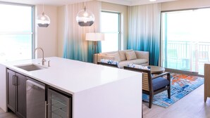 Une chambre d’hôtel moderne dotée d’un îlot de cuisine, d’un canapé et d’une table à manger.