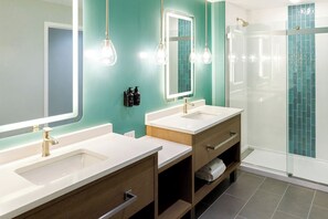 Ein modernes Badezimmer mit zwei Waschbecken, einem Spiegel und einer Dusche.