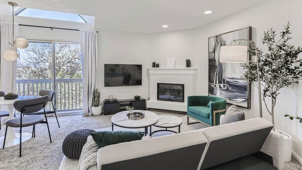 Een moderne woonkamer met een bank, stoelen, een salontafel, een open haard en een televisie.