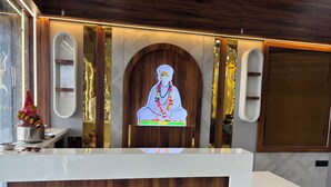 Ein Empfangstresen mit Holzverkleidung, einem gerahmten Porträt und einem kleinen Altar mit Blumen.