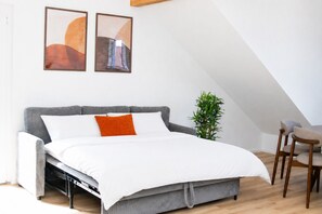A loft-style bedroom with a bed, a chair, a plant, and two abstract paintings on the wall. - In the middle of the wine region & Black Forest: Stylish apartment (Oberkirch)