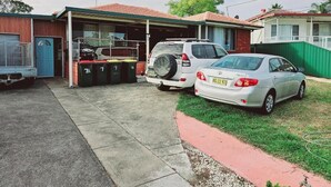 Un garage attenant à une maison, où sont garées deux voitures, avec une porte bleue et une allée carrossable couverte.