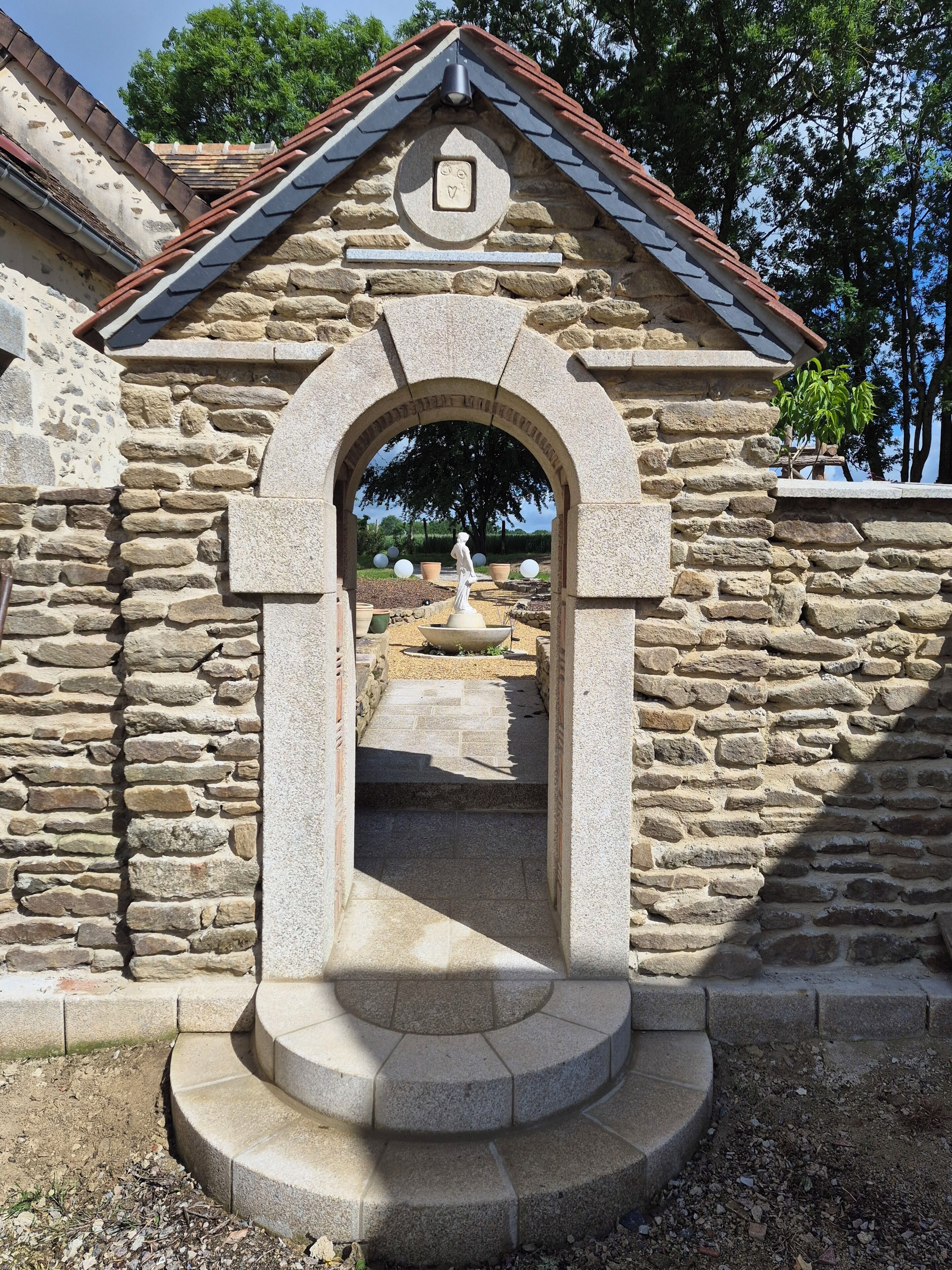 Une construction en pierre dotée d’une arche menant à une cour intérieure.