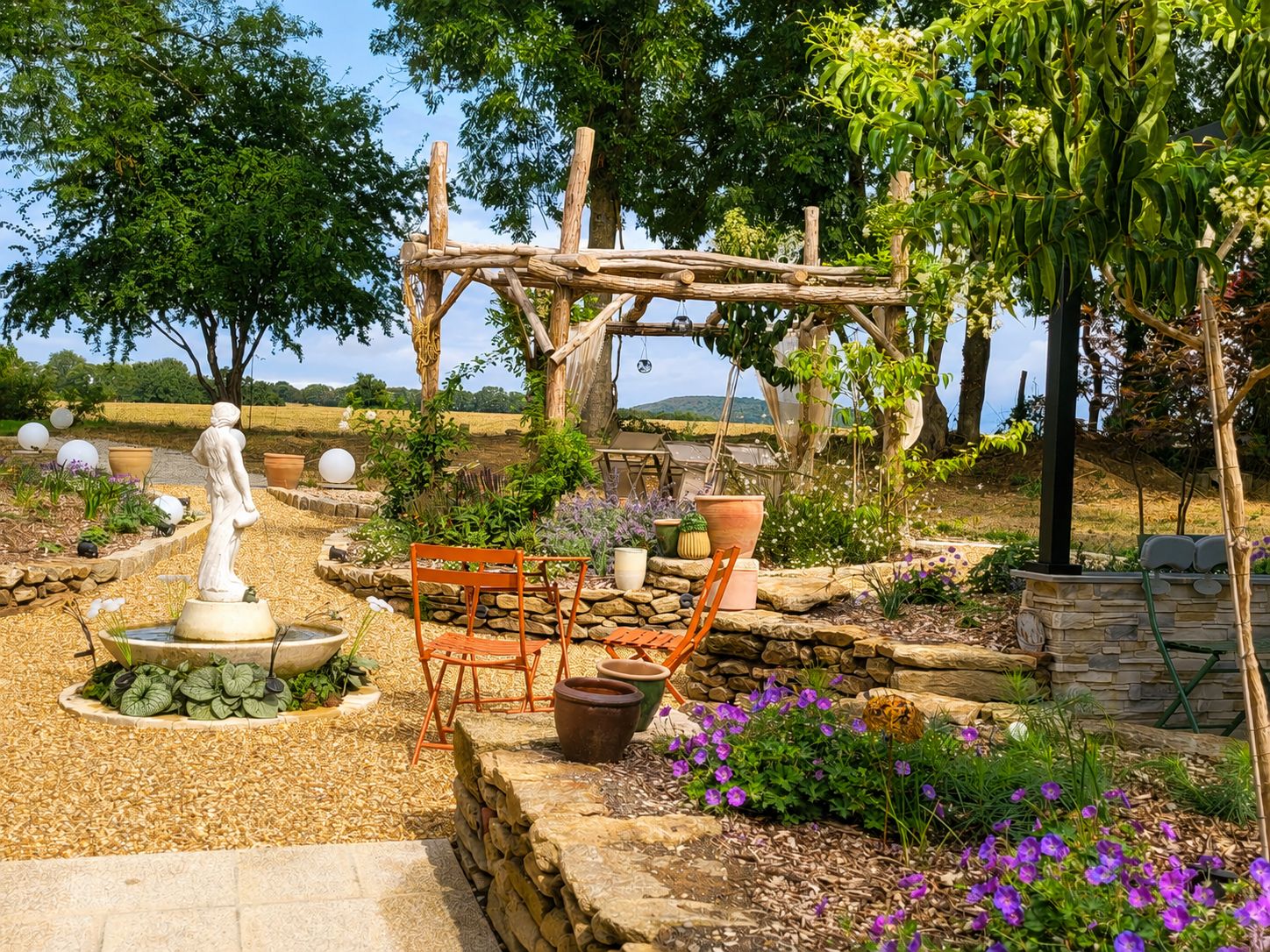 Jardín con estatua, pérgola de madera y mobiliario de exterior.