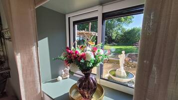 Une fenêtre donnant sur un jardin, avec un vase de fleurs et une statue.