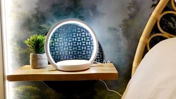 Une table de chevet avec un miroir rond et une petite plante en pot.