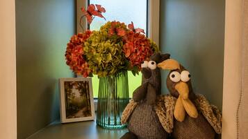 A small room with a window, a vase of flowers, and two plush toys on a shelf.
