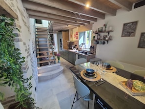 Une cuisine moderne avec un coin repas, un escalier et une vue sur l’extérieur.