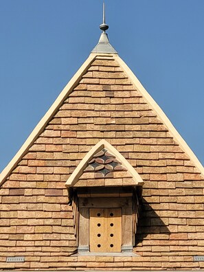 A building with a triangular roof and a small window with a decorative frame.