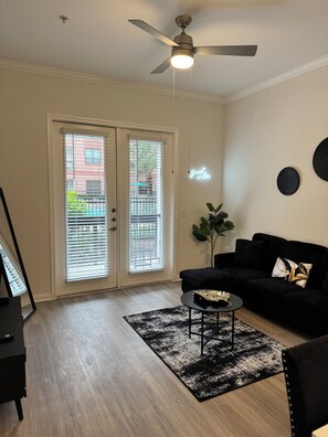 Ein Wohnzimmer mit Deckenventilator, einem schwarzen Sofa, einem Couchtisch und einem schwarz-weißen Teppich.
